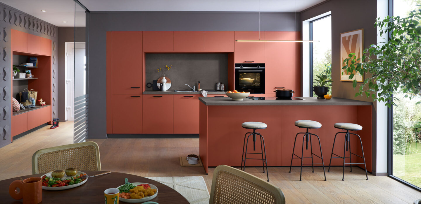 Moderne rote Küche mit Kücheninsel und schwarzer Arbeitsfläche bei Joecken Küchen in Düren