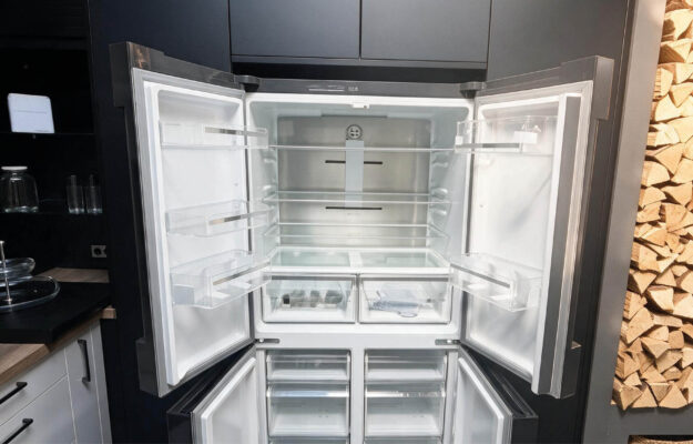 Geöffneter Bosch French-Door-Kühlschrank mit breitem Kühlraum, Glasablagen, Türfächern, Frischeschubladen und separaten Gefrierschubladen in der Ausstellungsküche.