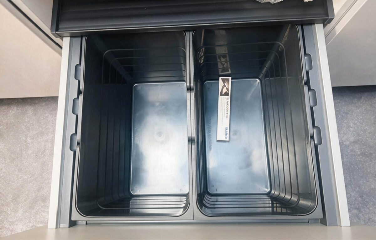 Ausziehbares Mülltrennsystem mit zwei großen Behältern in einem Unterschrank der modernen Häcker Küche – praktische Stauraumlösung für die Küchenplanung.