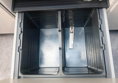 Ausziehbares Mülltrennsystem mit zwei großen Behältern in einem Unterschrank der modernen Häcker Küche – praktische Stauraumlösung für die Küchenplanung.