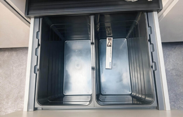 Ausziehbares Mülltrennsystem mit zwei großen Behältern in einem Unterschrank der modernen Häcker Küche – praktische Stauraumlösung für die Küchenplanung.