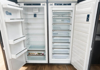 Geöffneter Liebherr Kühlschrank und Gefrierschrank nebeneinander mit Glasablagen, Türfächern, Frischeschublade und mehreren transparenten Gefrierschubladen.